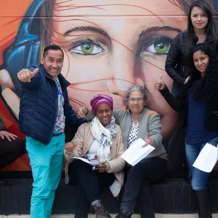 A group of people pose in front of street art