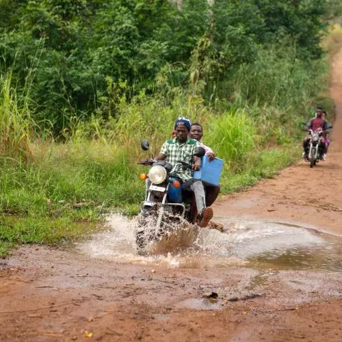 Motorbike driver and health worker delivering vaccines in rural sierra leone