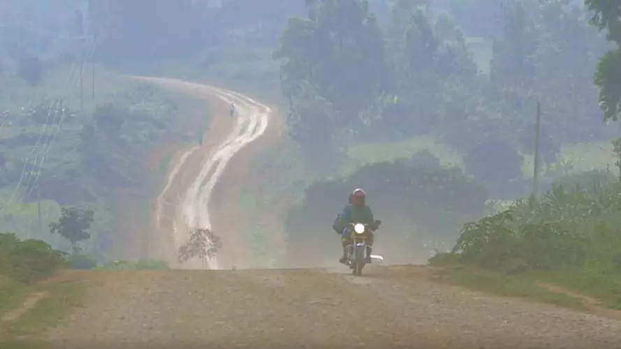 Person riding motorbike on dusty track through countryside in Western Kenya