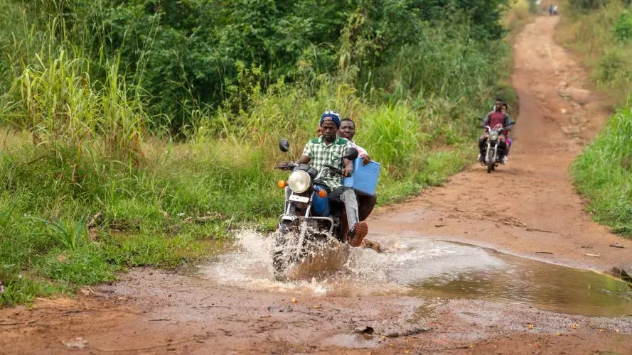 Motorbike driver and health worker delivering vaccines in rural sierra leone