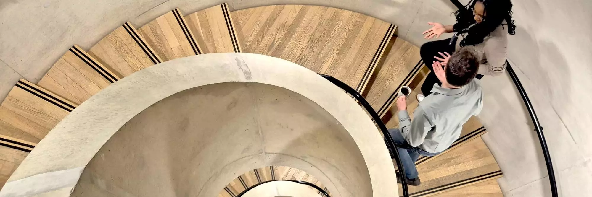 Two people walk up a spiral staircsae at the BSG