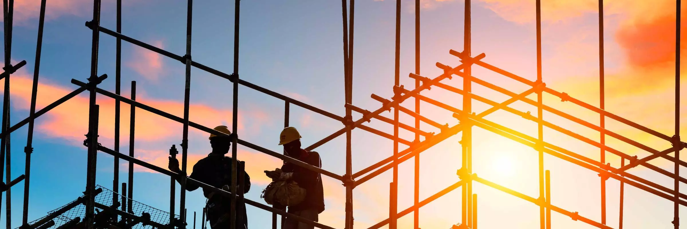 workers and construction site at sunset