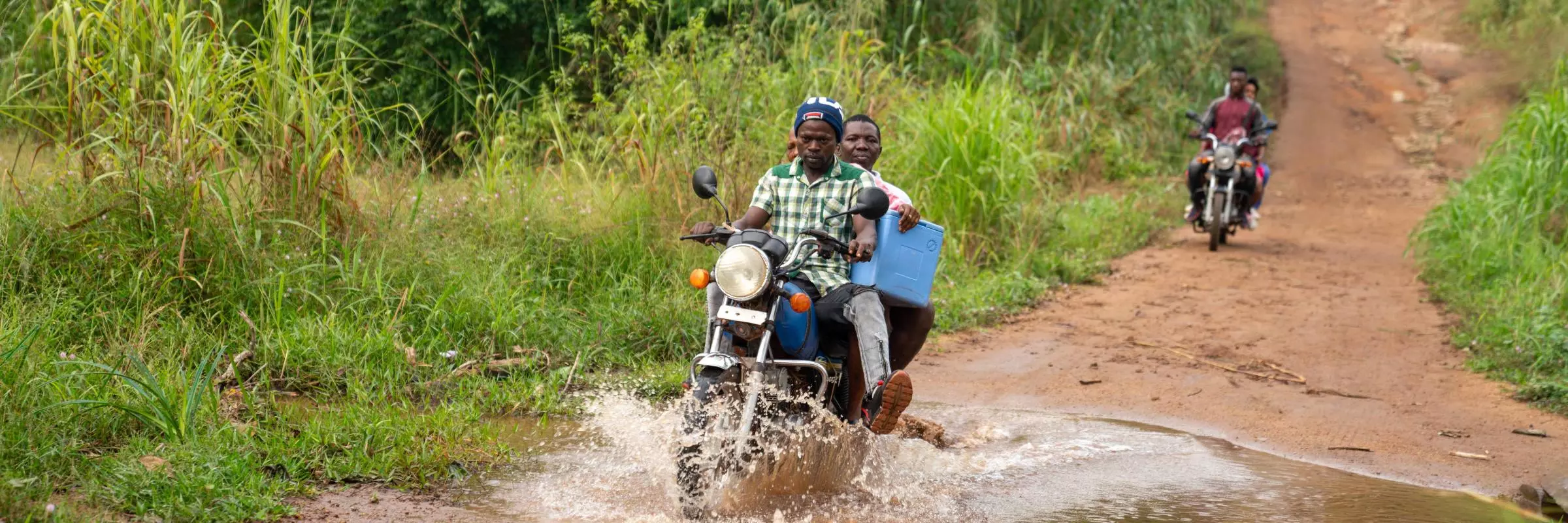 Motorbike driver and health worker delivering vaccines in rural sierra leone