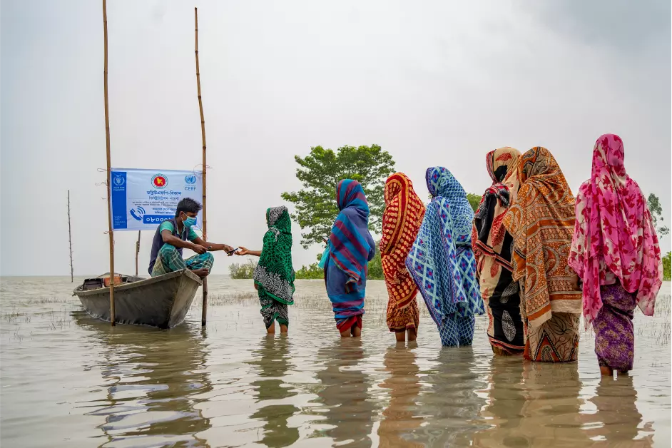 Women queueing at aid station in flood water in Bangladesh