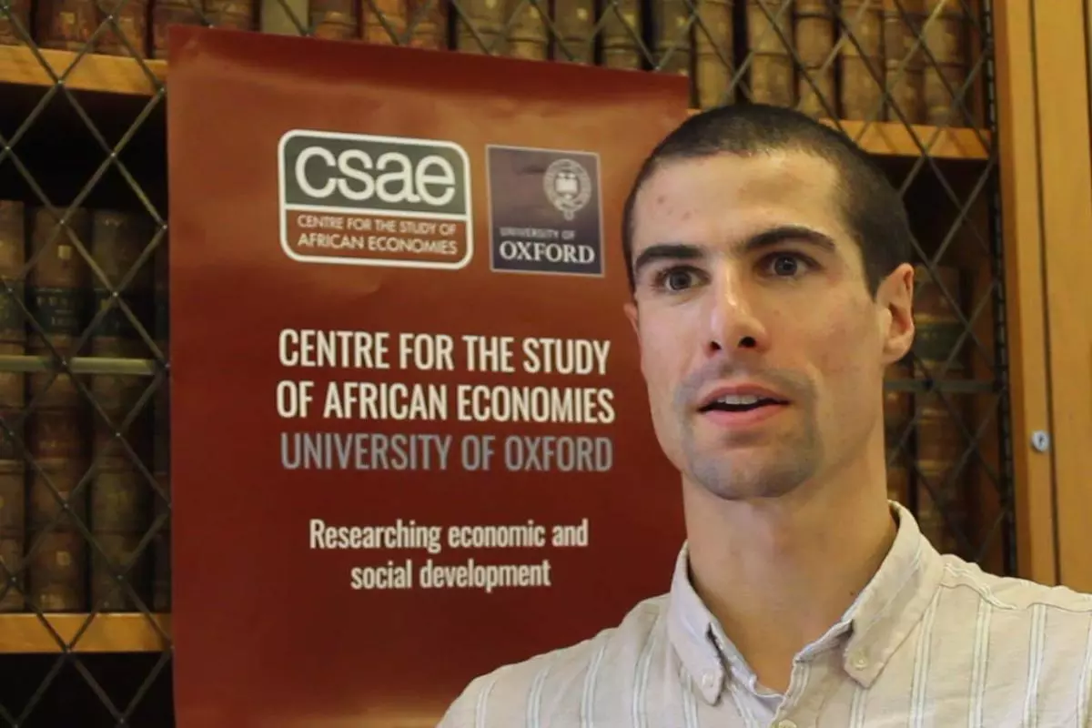 Rocco Zizzamia screenshot as he talks in a video in front of a CSAE poster